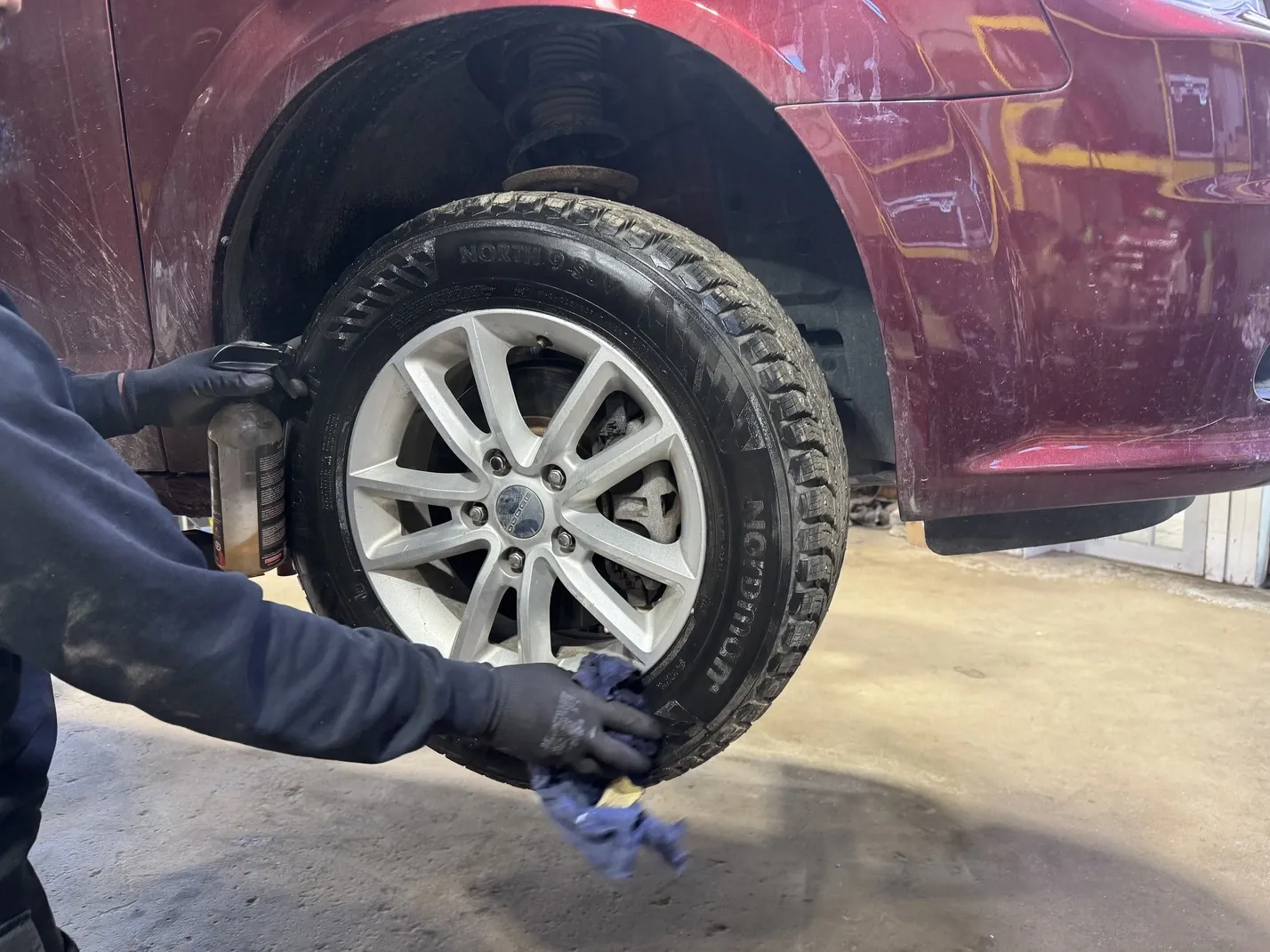Mécanicien de DG entretenant une roue avec pneu d'hiver dans l'atelier